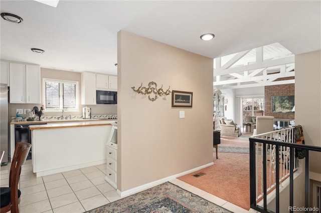 kitchen featuring a healthy amount of sunlight, black appliances, white cabinets, and light tile patterned flooring