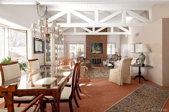 carpeted dining room with visible vents, a chandelier, beamed ceiling, a brick fireplace, and high vaulted ceiling