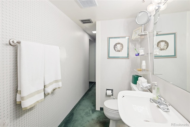 bathroom featuring toilet, a sink, and visible vents