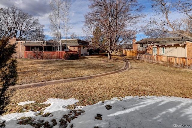 yard covered in snow with covered porch and fence