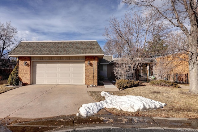 view of front facade featuring an attached garage, brick siding, a shingled roof, fence, and concrete driveway