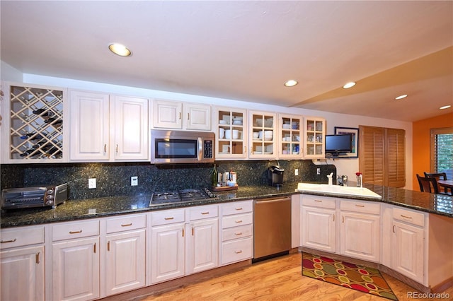 2141 S Dallas St, Denver, CO 80231 - kitchen featuring appliances with stainless steel finishes, a peninsula, backsplash, glass insert cabinets, and recessed lighting