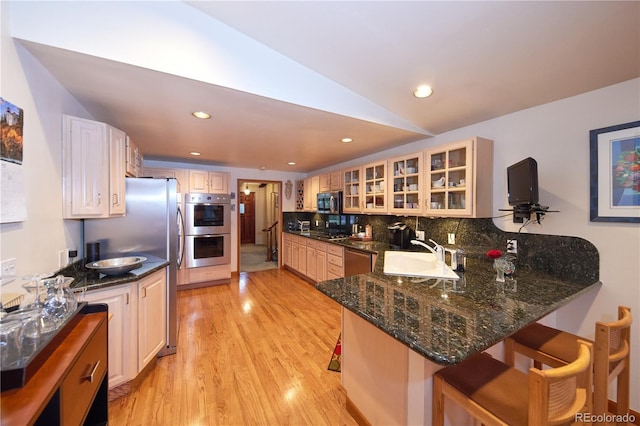 2141 S Dallas St, Denver, CO 80231 - kitchen with stainless steel appliances, light wood-type flooring, decorative backsplash, a kitchen breakfast bar, and a peninsula