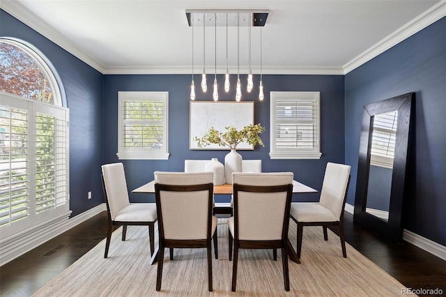 dining room with baseboards, wood finished floors, and crown molding