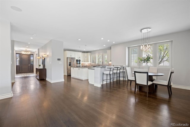 living room with dark wood-style flooring, a chandelier, baseboards, and recessed lighting