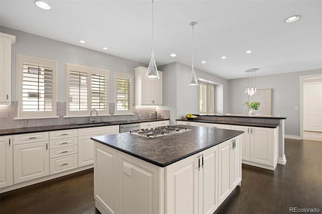 kitchen featuring a center island, a sink, appliances with stainless steel finishes, dark countertops, and recessed lighting