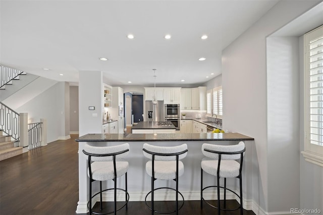 kitchen featuring appliances with stainless steel finishes, dark wood-style flooring, recessed lighting, a kitchen breakfast bar, and a kitchen island