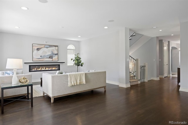 living room with stairs, wood finished floors, baseboards, recessed lighting, and a glass covered fireplace
