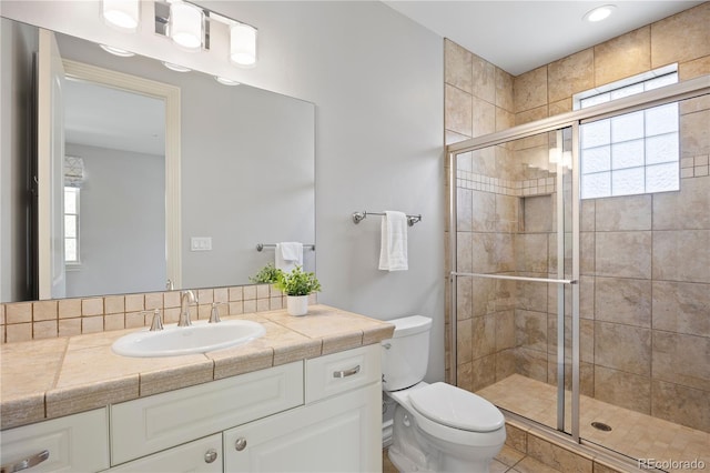 bathroom with a stall shower, toilet, and vanity