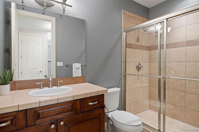 bathroom with a stall shower, toilet, and vanity