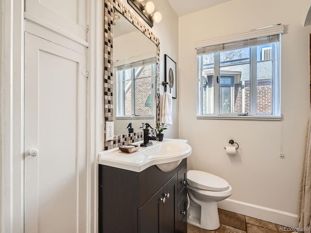 bathroom featuring toilet, baseboards, and vanity