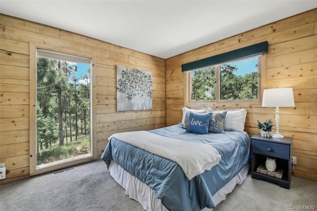 bedroom featuring access to exterior, wooden walls, carpet flooring, and visible vents