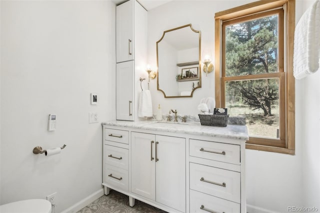 bathroom featuring vanity, toilet, and baseboards