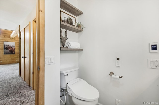 bathroom featuring wooden walls and toilet