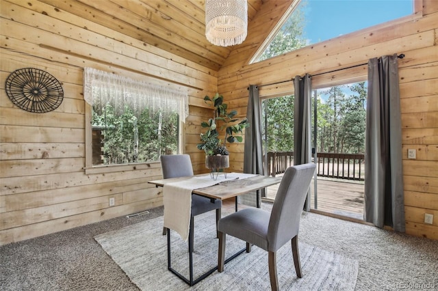 dining space with lofted ceiling, wooden walls, and carpet flooring