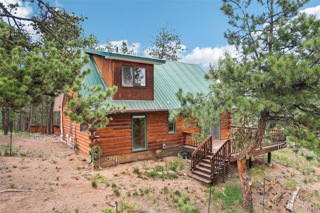 back of house featuring metal roof, a deck, and driveway