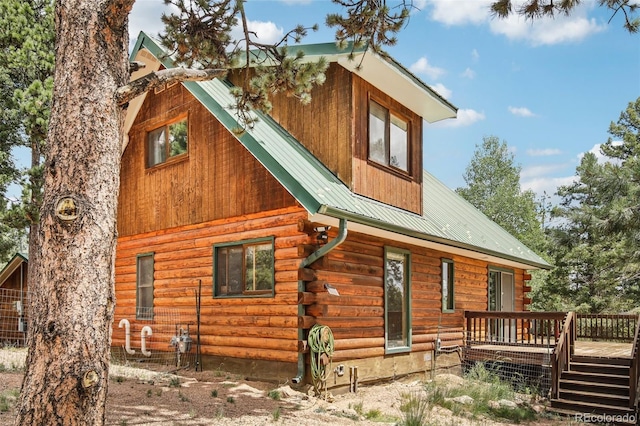 rear view of house featuring a wooden deck, log exterior, and metal roof