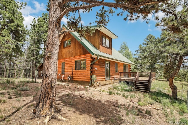 view of property exterior with a wooden deck, log exterior, and metal roof