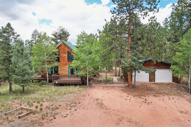 view of front of home with a garage, a wooden deck, and an outdoor structure