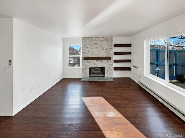 unfurnished living room featuring a wall mounted AC, a fireplace, dark wood-type flooring, and a baseboard heating unit