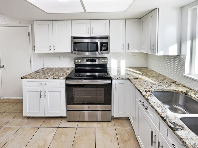 kitchen with white cabinets, light tile patterned flooring, and appliances with stainless steel finishes