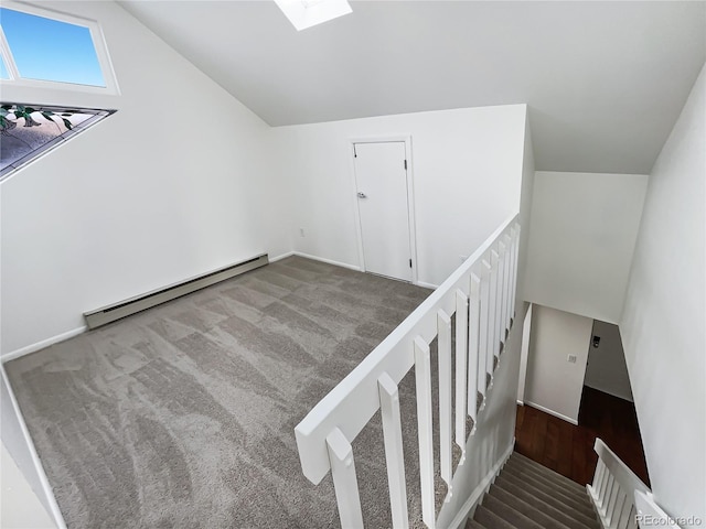 stairs with carpet floors, lofted ceiling with skylight, and baseboard heating