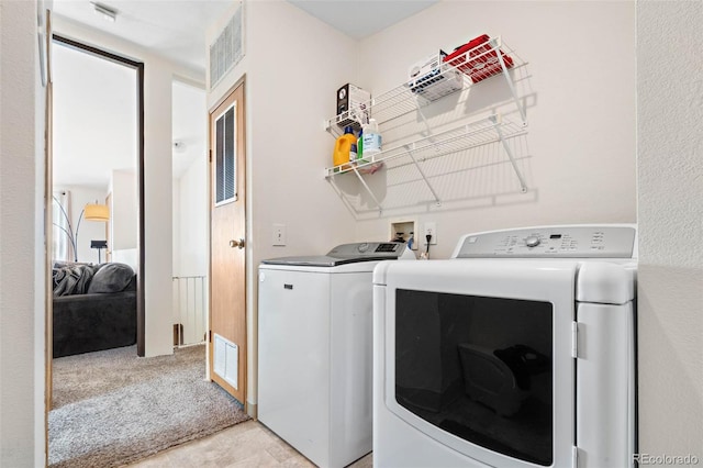 clothes washing area with light carpet, laundry area, washing machine and dryer, and visible vents