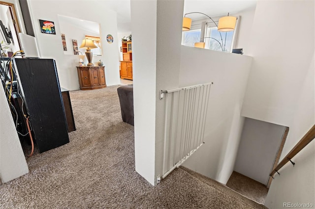 hallway featuring an upstairs landing and carpet