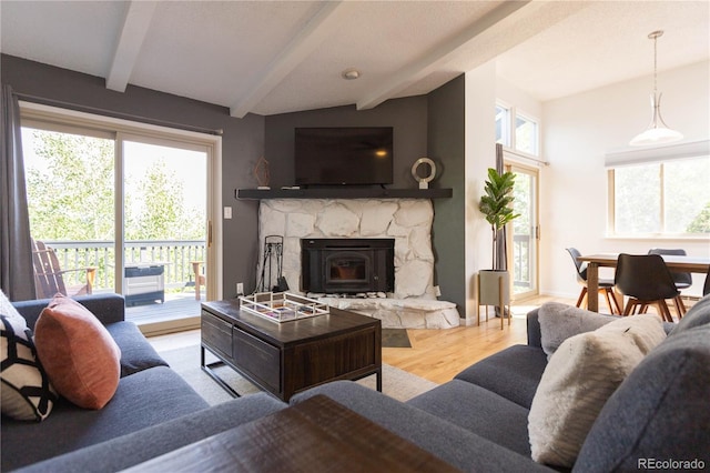 living room featuring a fireplace, wood finished floors, a healthy amount of sunlight, and beam ceiling