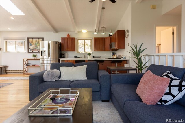 living room featuring a skylight, light wood-type flooring, recessed lighting, beamed ceiling, and a ceiling fan