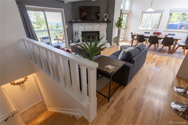 living area featuring a healthy amount of sunlight, wood finished floors, and a stone fireplace