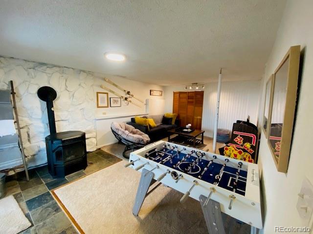 recreation room featuring a wood stove and a textured ceiling