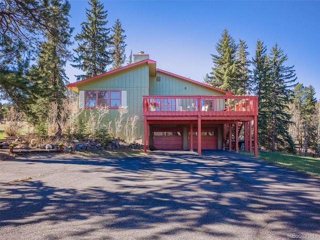 8473 Gray Fox Dr, Evergreen, CO 80439 - chalet / cabin with an attached garage, aphalt driveway, a chimney, and a deck