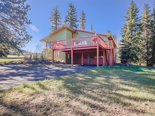 8473 Gray Fox Dr, Evergreen, CO 80439 - view of front facade with an attached garage, a front yard, a deck, and aphalt driveway