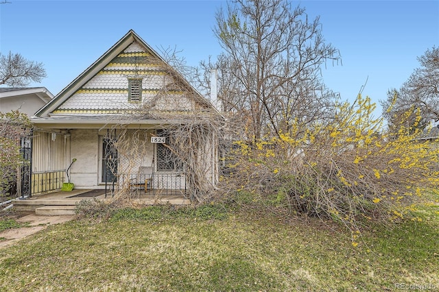 victorian home featuring a porch, stucco siding, and a front lawn