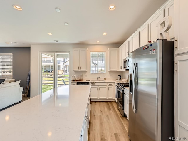 9054 Truckee Ct, Commerce City, CO 80022 - kitchen with stainless steel appliances, white cabinets, recessed lighting, light wood-style flooring, and light stone counters