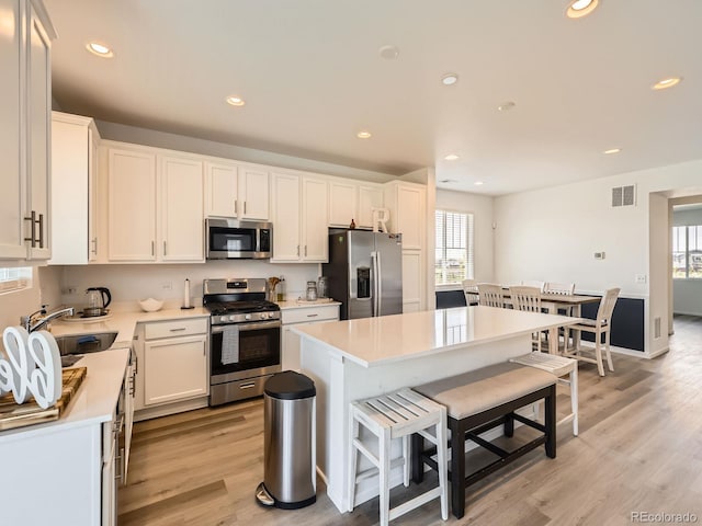 9054 Truckee Ct, Commerce City, CO 80022 - kitchen featuring appliances with stainless steel finishes, a breakfast bar area, plenty of natural light, light wood-style flooring, and recessed lighting