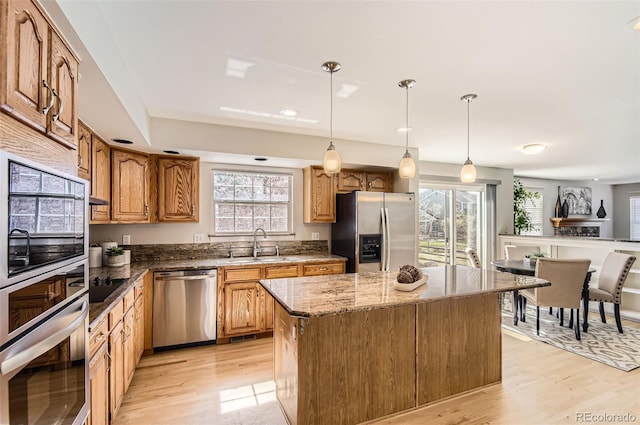1516 Saltbush Ridge Rd, Highlands Ranch, CO 80126 - kitchen with light wood-type flooring, dark stone countertops, a kitchen island, appliances with stainless steel finishes, and a sink