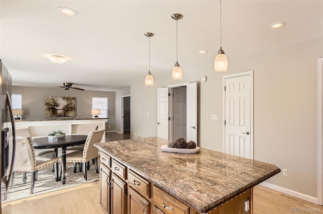 1516 Saltbush Ridge Rd, Highlands Ranch, CO 80126 - kitchen with light stone countertops, light wood-style floors, brown cabinetry, and ceiling fan