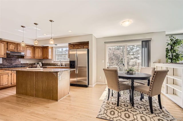 1516 Saltbush Ridge Rd, Highlands Ranch, CO 80126 - kitchen featuring light wood-style floors, stainless steel refrigerator with ice dispenser, a center island, under cabinet range hood, and a sink
