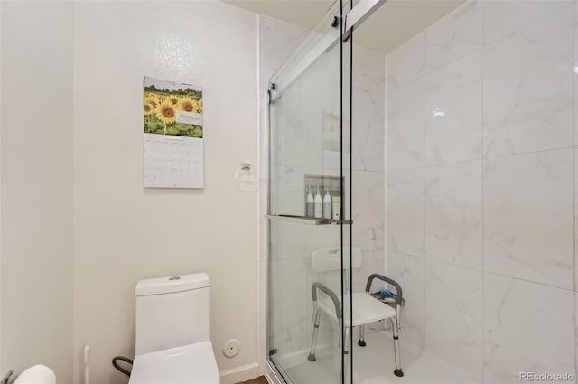 bathroom featuring a shower with door and toilet