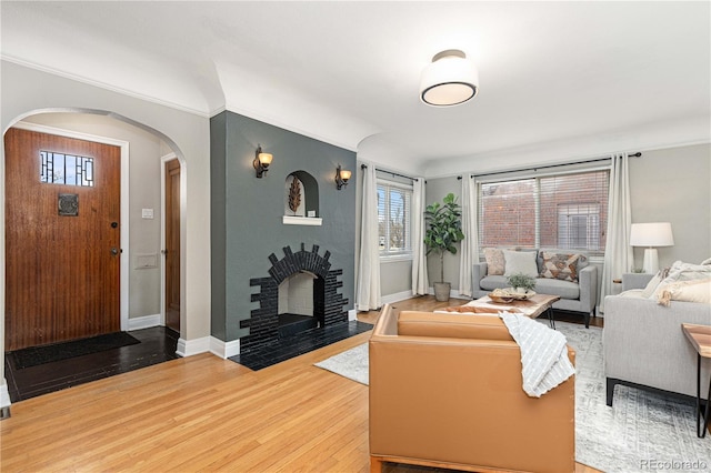 living room featuring a brick fireplace, crown molding, and hardwood / wood-style flooring