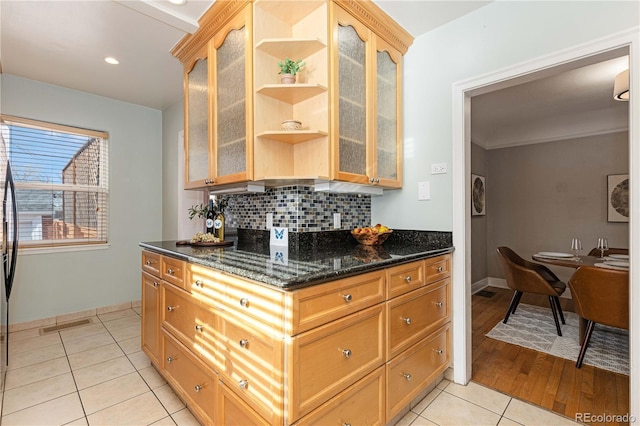 kitchen featuring light tile patterned floors, backsplash, and dark stone countertops