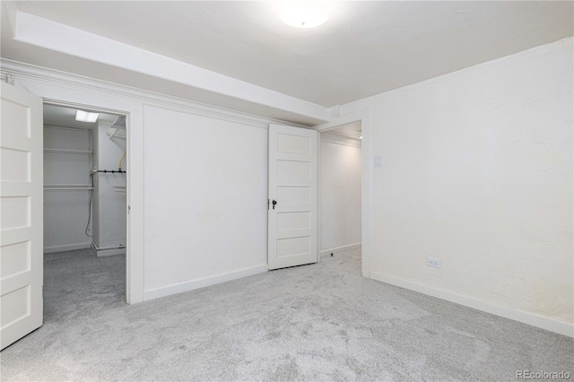 unfurnished bedroom with light carpet, a walk in closet, and a closet