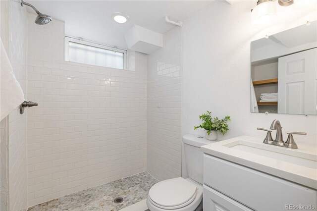 bathroom featuring toilet, vanity, and tiled shower