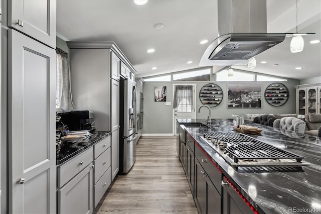 kitchen with stainless steel appliances, lofted ceiling, light wood-style floors, a sink, and dark stone countertops