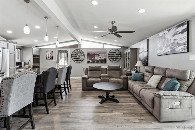 living room featuring vaulted ceiling with beams, light wood-style flooring, and recessed lighting