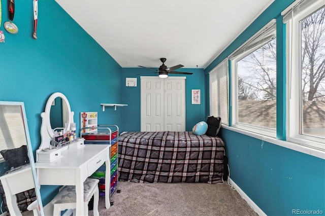 carpeted bedroom featuring ceiling fan, multiple windows, baseboards, and a closet