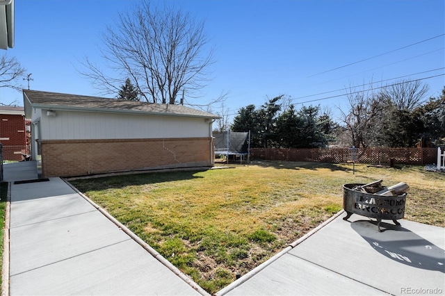 view of yard with a trampoline and fence