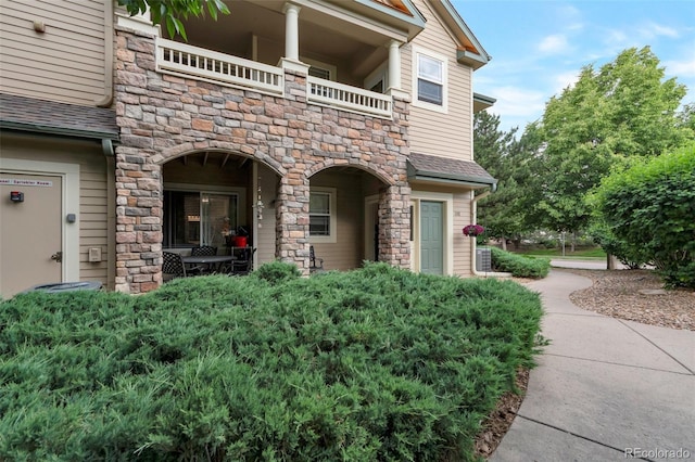8338 S Independence Cir Unit 108, Littleton, CO 80128 - entrance to property with a balcony, stone siding, and a shingled roof